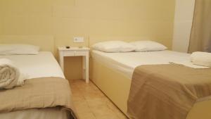 a room with two beds and a table with a night stand at Enalio Rooms in Glida