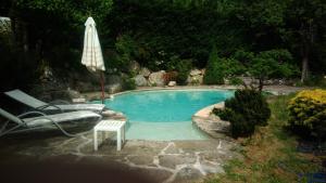 - une piscine avec une chaise et un parasol dans l'établissement Le Cloterriou, à Braux