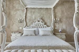 a bedroom with a white canopy bed with white furniture at La Zarabba Boutique Hotel in Ponti Sul Mincio