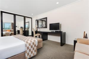 a hotel room with a large bed and a television at Hotel on Devonport in Tauranga