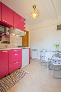 a kitchen with red cabinets and a table and a dining room at Appartment Happy Time in Matulji