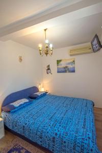 a bedroom with a blue bed and a chandelier at Appartment Happy Time in Matulji