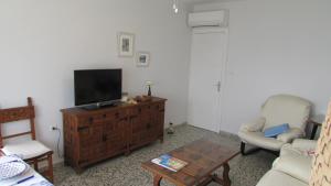 a living room with a television on a wooden dresser at Apartamento 1º linea playa Torrenueva, Motril, Granda in Torrenueva