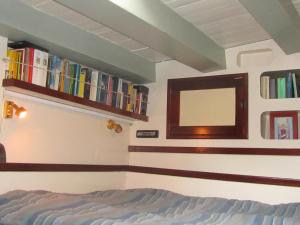 1 dormitorio con 1 cama y libros en la pared en Zeilschip Fortuna en Medemblik