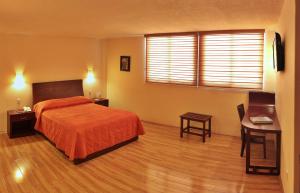 a bedroom with a bed and a table and a desk at Hotel CR Tehuacan in Tehuacán