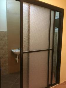 a bathroom with a shower door and a sink at Brown Epitome Lodge in Baler +4 photos