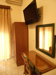 a room with a table and a television on a wall at Hotel Admitos in Volos