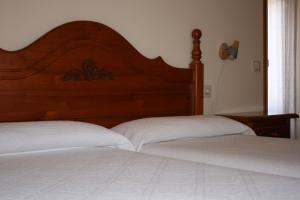 a bedroom with two white beds and a wooden headboard at Hostal La Catalana in Sant Llorenç de Morunys