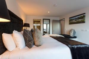 a bedroom with a large white bed with pillows at Views on Hallenstein in Queenstown