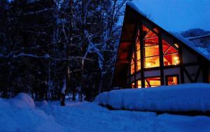 una casa con una ventana iluminada en la nieve por la noche en Yuki-ki Lodge, en Hakuba