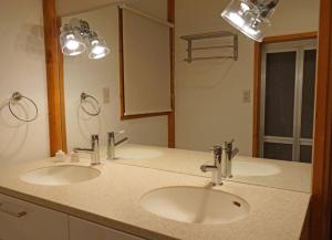 Un baño con dos lavabos y un espejo grande. en Yuki-ki Lodge, en Hakuba