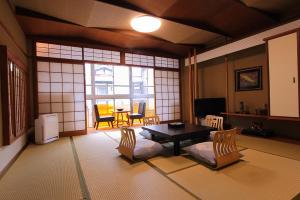 een woonkamer met een tafel en stoelen en een raam bij Sinonomesou in Toyooka