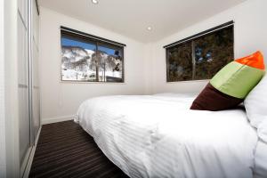a bedroom with a white bed and two windows at Sky Park Happo Chalet in Hakuba