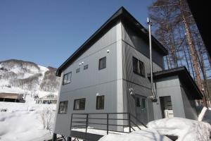 a white building with a black roof in the snow at Sky Park Happo Chalet in Hakuba