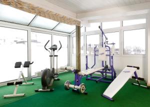 a gym with treadmills and exercise equipment and windows at Kurhotel Luitpold in Bad Wörishofen
