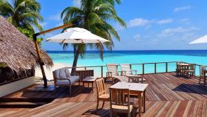 Makunudhoo的住宿－馬庫努都島，一个带桌椅和遮阳伞的甲板和大海