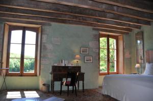 a bedroom with a bed and a desk and windows at Domaine du Ris de Feu Chambres d'hôtes de charme in Chalais +70 photos