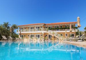 a hotel with a swimming pool in front of a building at Artemis Apartments in Kypseli