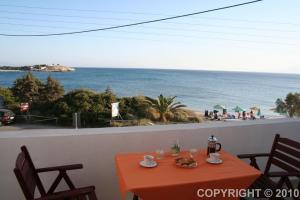 una mesa de naranja con sillas y vistas a la playa en Margaritis Apartments, en Agia Anna de Naxos