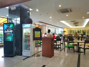 um restaurante com uma máquina de refrigerantes e pessoas sentadas às mesas em Dohera Hotel em Cebu
