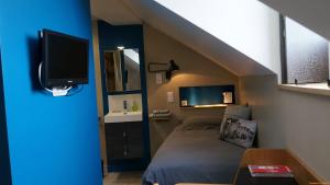 a small bedroom with a bed and a tv at Abri du Passant in Roubaix