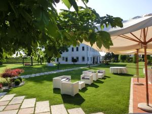 trawnik z białymi krzesłami i biały budynek w obiekcie Villa Dei Dogi w Caorle