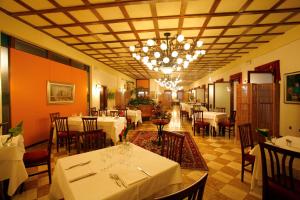 un restaurante con mesas y sillas blancas y una lámpara de araña en Villa Dei Dogi, en Caorle