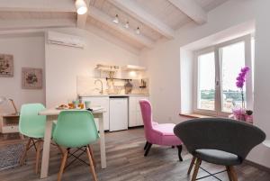 a kitchen and dining room with pink and green chairs at Apartments and Rooms Hey Rovinj in Rovinj