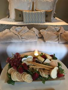 a plate of food with cheese and fruit on a bed at Spa Suites at RAVEN in Hepburn Springs