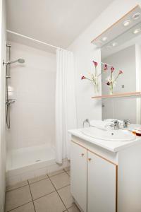 a white bathroom with a sink and a shower at Séjours & Affaires Caen Le Clos Beaumois in Caen