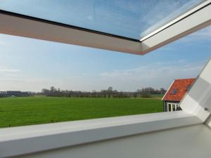 ein Fenster mit Blick auf ein grünes Feld in der Unterkunft Stylish Holiday Home With Garden Near Oostkapelle in Oostkapelle
