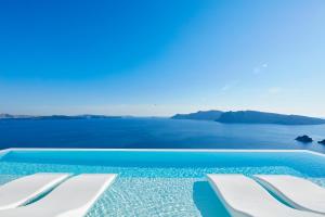 イアにあるCanaves Oia Suites - Small Luxury Hotels of the Worldの海の景色を望むプール(白い椅子付)