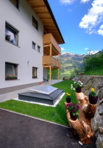 a house with a garden with potted plants on the lawn at Apartment Sonnbichl in Schwendau