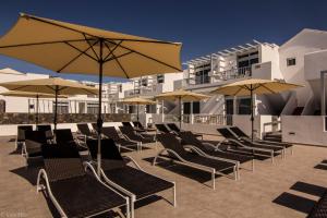 szereg leżaków i parasoli na patio w obiekcie Los Gracioseros 118 & 202 w Puerto del Carmen