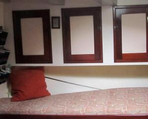 a bedroom with three windows and a red pillow at Zeilschip Fortuna in Medemblik