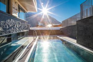 a house with a pool with the sun in the background at Chalet Hohe Welt - luxury apartments in Lech am Arlberg