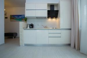 una cucina con armadi bianchi e lavandino di Apartament Ultra Lux a Mamaia