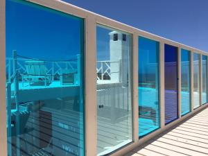 a balcony with glass windows and a view of a lighthouse at Daranur in Essaouira
