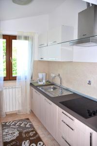 a white kitchen with a sink and a window at Sea view apartmant Nona with pool in Ližnjan