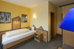 1 dormitorio con 1 cama y mesita de noche con lámpara azul en Globotel Business en Garbsen