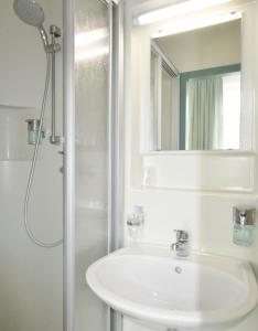 a white bathroom with a sink and a shower at Hotel Ostseestern in Kühlungsborn