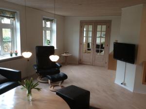 Axelgaard Guest Rooms في Ovtrup: غرفة معيشة مع طاولة وكراسي وتلفزيون