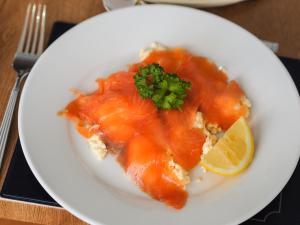 a white plate of food with salmon and a lemon at Bay Lodge Guest House in Eastbourne