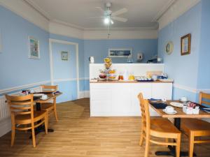 una cocina con paredes azules y mesas y sillas de madera. en Bay Lodge Guest House en Eastbourne