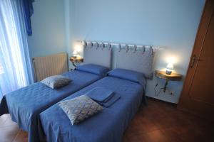 アジェーロラにあるPalazzo Mascoloのベッドルーム1室(ベッド2台、青いシーツ、ランプ2つ付)