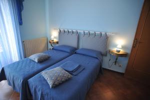 a bedroom with two beds with blue sheets and two lamps at Palazzo Mascolo gruppo mascololuxuryapartments in Agerola