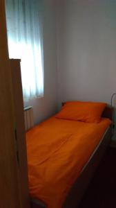 an orange bed in a room with a window at New Point in Zagreb