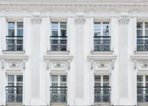 パリにあるホテル デュ ロマンシエの窓とバルコニー付きの白い建物