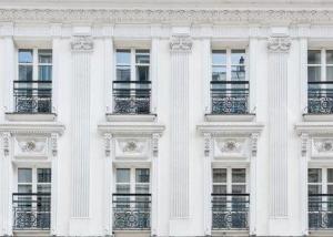 a white building with windows and balconies at Hôtel du Romancier in Paris