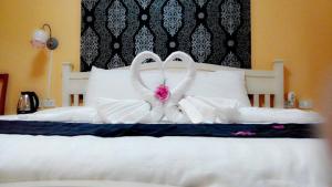 dois cisnes feitos de almofadas numa cama em Ploy Puu Residence em Chiang Rai
